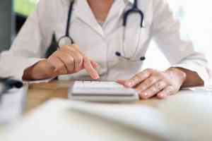 Ärztin arbeitet auf Taschenrechner im Büro